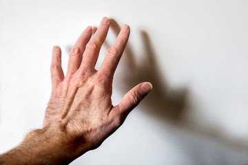 Man&rsquo;s hand touching white wall - mental health concept.