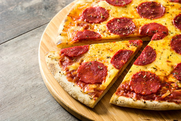 Hot italian pepperoni pizza sliceon wooden table. 
