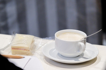 sandwish on dish and white coffee cup with hot cappuccino coffee inside put on  table