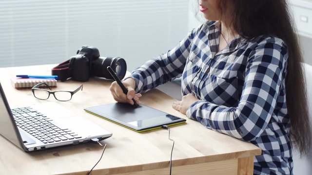Woman graphic designer working with digital drawing tablet and pen on a computer
