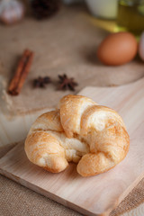 Croissant on wooden cut board on table wood and fabric select focus shallow depth of field