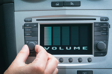 Driver adjusting volume in the car audio system