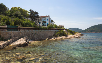 Buildings rise above the stony beach of the sea