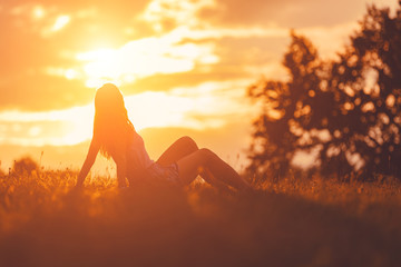 Girl enjoying in the meadow at golden sunset time.