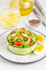 Fresh salad with crayfish necks, lettuce, cherry tomatoes, egg in a ring of cucumbers