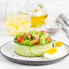 Fresh salad with crayfish necks, lettuce, cherry tomatoes, egg in a ring of cucumbers