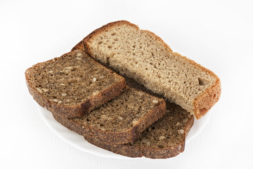 Black and white bread on a white plate on a white isolated background.