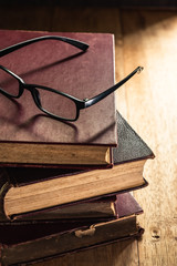 glasses on the pile of old books in vintage tone