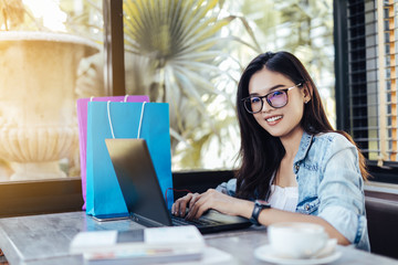 Young asian woman smile and using laptop computer. Online shopping concept