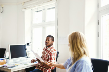 Coworker passing document to colleague in office