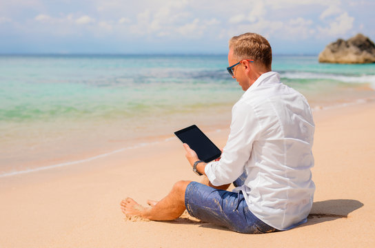 Businessman with tablet on the beach