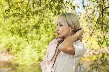 Blonde woman outdoors on green foliage leaves background
