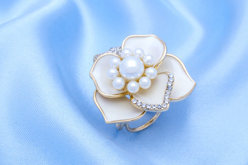 gold brooch flower with a pearls and diamonds isolated on silk