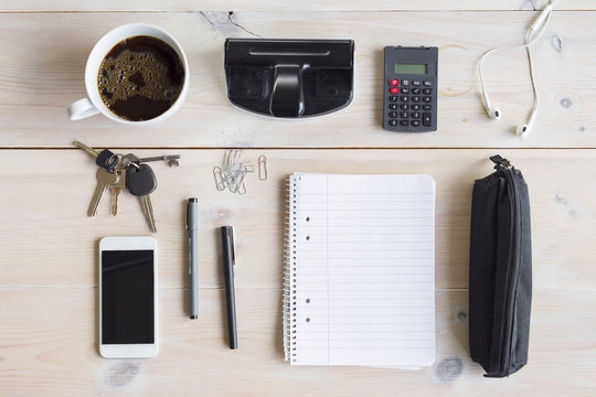 Office supplies, smart phone, keys and coffee cup on desk