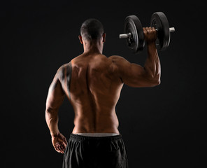 Fototapeta na wymiar Strong handsome sport man making weightlifting and exercising the shoulders on isolated black background