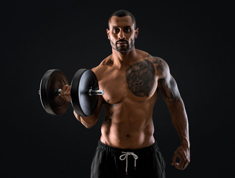 Strong handsome sport man making weightlifting and exercising the biceps on isolated black background