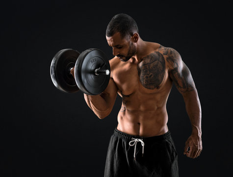 Strong handsome sport man making weightlifting and exercising the biceps on isolated black background