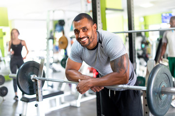 Strong handsome sport man resting after exercise at the gym