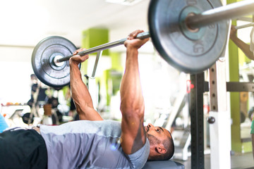 Fototapeta na wymiar Strong handsome sport man doing chest exercises in the gym