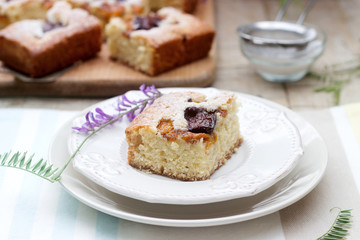 Pieces of fruit pie with pieces of plums and peach and a bouquet of flowers on a wooden table. Rustic style.