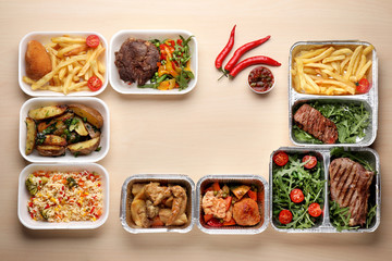 Different containers with delicious food on wooden table. Delivery service