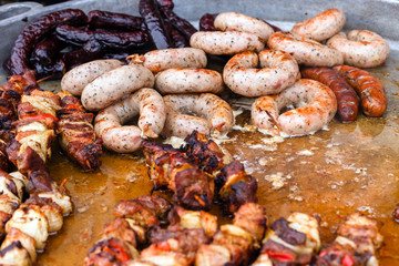 Delicious fresh sausages and kebab fried on large frying pan at outdoor cafe.