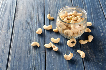 Fototapeta na wymiar Tasty cashew nuts and glass jar on wooden background