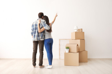 Fototapeta na wymiar Young couple hugging near boxes indoors. Moving into new house