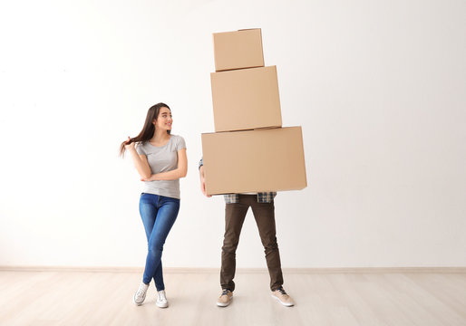 Young couple with boxes indoors. Moving into new house
