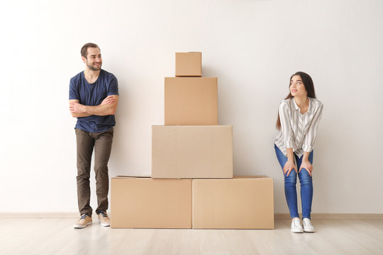 Young couple near tower made of boxes indoors. Moving into new house