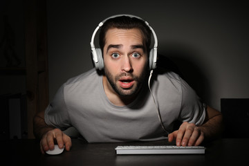 Young man playing video games on computer at home