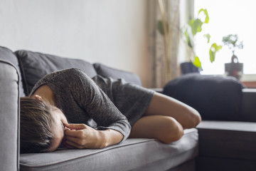 Pensive woman lying down on sofa