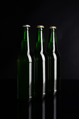 Fresh beer in glass bottles on black background