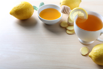 Cup of delicious tea with ginger, lemon and honey on table