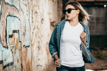 Girl wearing t-shirt and cotton jacket posing against street , urban clothing style. Street...