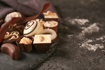 Slate plate with different tasty chocolate candies on textured table