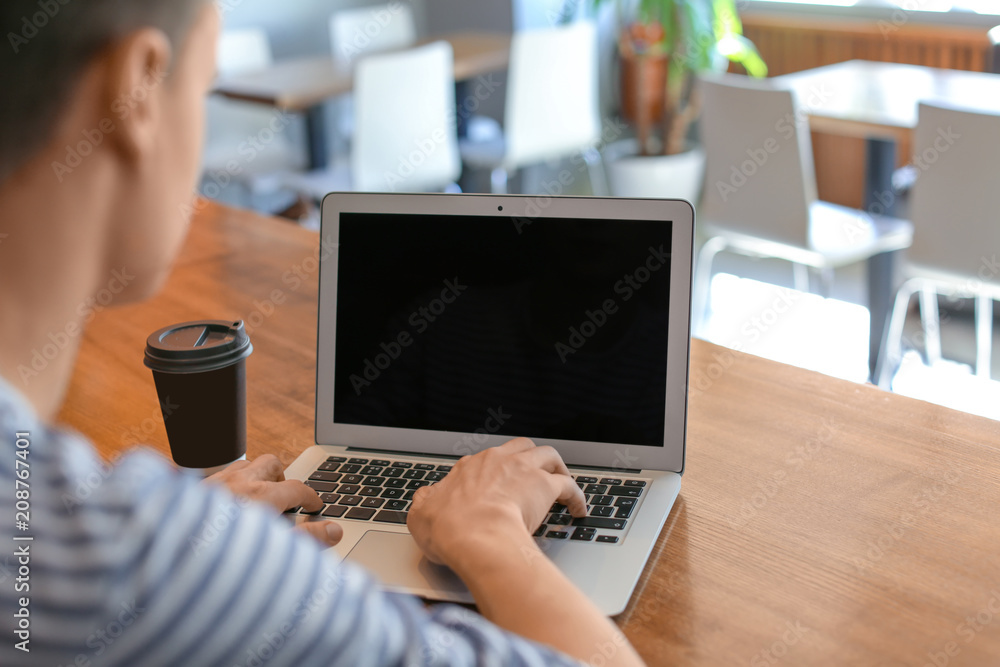 Canvas Prints Young man using laptop at table in cafe