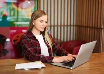 Young woman with laptop and mail at table in cafe