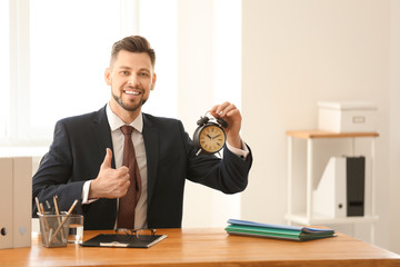 Businessman with alarm clock at table in office. Time management concept