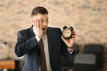 Businessman with alarm clock in office. Time management concept