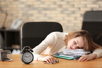 Mature tired woman sleeping at table in office. Time management concept