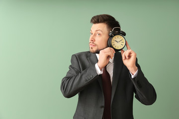 Businessman with alarm clock on color background. Time management concept