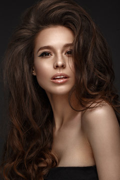 Beautiful brunette model with volume curls, classic makeup and sexy lips. The beauty of the face. Portrait shot in the studio.
