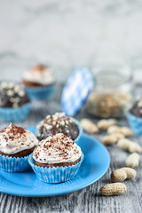 Tasty chocolate cupcakes on a grey wooden background with chocolate and nuts
