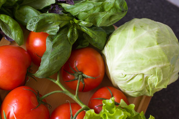 Vegetables and fresh herbs on a wooden board against the background of a kitchen table. Proper healthy eating. Vegetarianism.