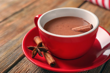 Cup of yummy hot chocolate with cinnamon on wooden table