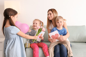 Mother receiving gifts from her cute little children at home