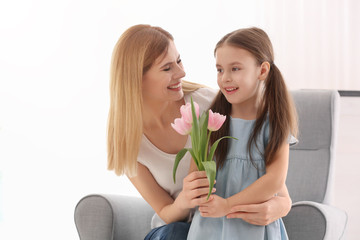 Mother receiving flowers from her cute little daughter at home