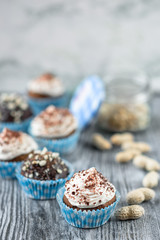 Tasty chocolate cupcakes on a grey wooden background with chocolate and nuts