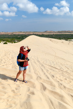 traveler holding camera at white sand dune desert